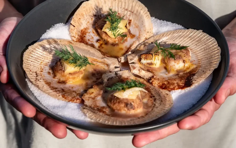 Hands holding a plate of grilled seafood
